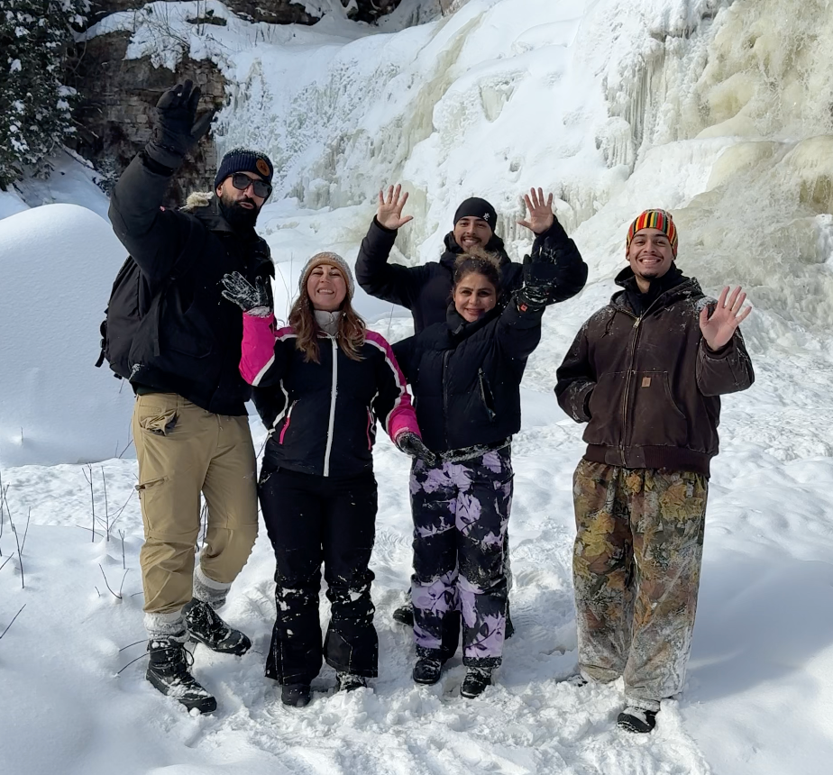 Five people posing in the snow with icy cliffs in the background